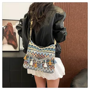 Detail of bohemian woven crossbody bag with colorful zigzag patterns and fringe tassels