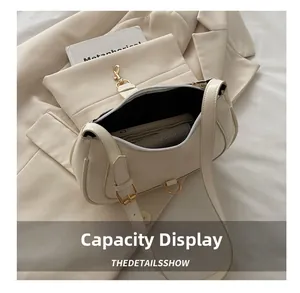 Capacity display of a beige baguette bag with gold hardware and interior storage details