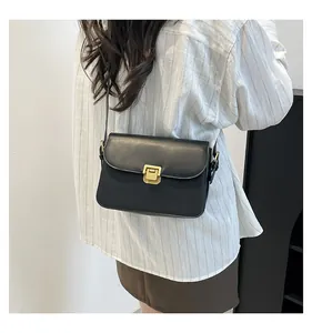 Chic black crossbody bag with golden metal buckle clasp shown on model for fashion display