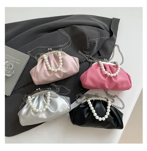 Top view of pleated cloud bags in pink, silver and black with pearl handles and chain