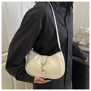 Detail of glossy off-white hobo bag with a sleek metallic gold hook buckle