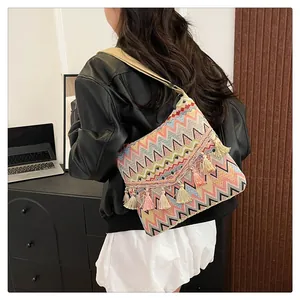 Detail view of large bohemian knit shoulder bag with colorful wave patterns and fringe