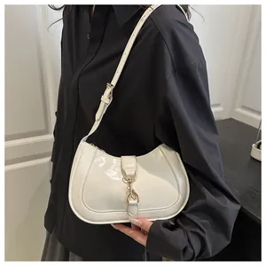 Close-up of white glossy patent leather baguette bag with elegant gold metal buckle detail
