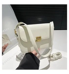 Detail view of cream crossbody bag with gold square buckle and adjustable shoulder straps
