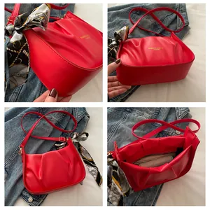 Dettaglio della borsa a tracolla rossa a pieghe con logo moda e foulard di seta sul manico