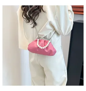 Detail of pink cloud-shaped crossbody bag with pearl handle and metal clip closure