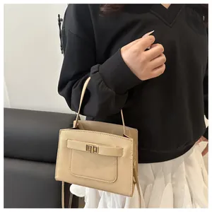 Dettaglio della pelle a grana incrociata e fibbia in metallo dorato su borsa beige