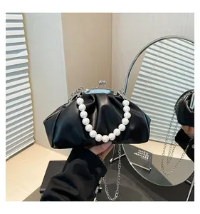Detailed view of black pleated cloud bag with elegant pearl handle and metal clasp