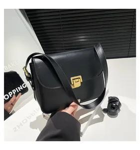 Detail view of black leather crossbody bag with gold rectangular clasp and mirror reflection