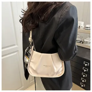 Chic sac à bandoulière plissé beige avec foulard en soie sur un blazer noir