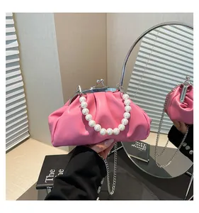Detail of bright pink pleated cloud bag with pearl handle and metal chain strap