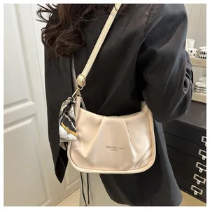 Dettaglio borsa a spalla beige a pieghe con testo moda e sciarpa di seta decorativa