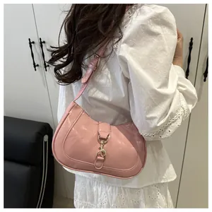 Detail of light pink glossy leather underarm bag with decorative strap and metal buckle