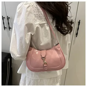 Detail of pink patent leather baguette bag with a gold piston lock on the shoulder