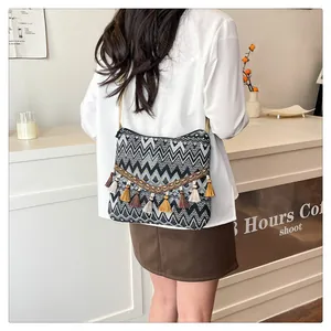 Detail of ethnic crossbody bag featuring black and white woven patterns and colorful tassels