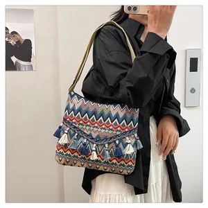 Detail of bohemian woven shoulder bag with colorful zigzag patterns and tassel fringe edge