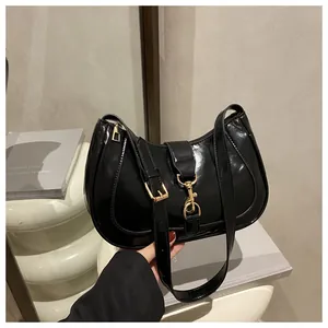 Detail of black glossy hobo bag featuring shiny patent leather and gold hardware accents