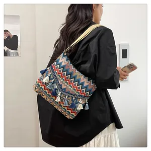 Close-up of bohemian shoulder bag featuring colorful wavy patterns and long fringe tassels
