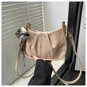 Détail du sac à bandoulière plissé beige avec écharpe décorative et lettrage mode