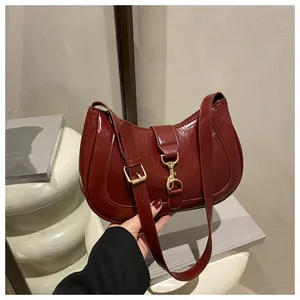 Detailed view of burgundy patent leather hobo bag featuring a gold-toned piston clasp