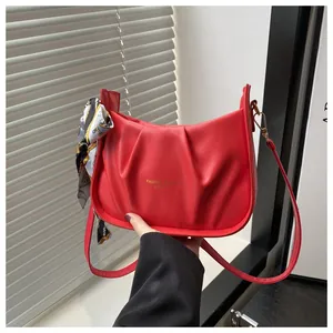 Détail du sac demi-lune rouge plissé avec foulard élégant et logo doré brillant
