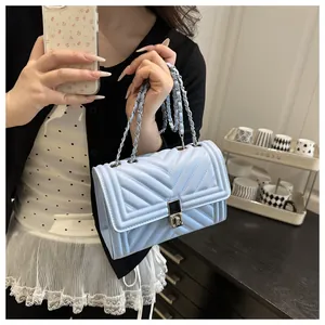 Detail of light blue quilted crossbody bag with V-shaped stitching and gold chain