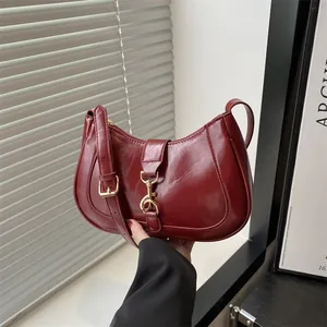 Deep red semi-circle shoulder bag with gold clasp and glossy finish in retro style