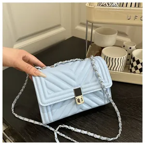 Close-up of light blue quilted leather texture with silver chain and metal turn-lock
