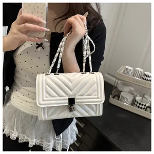 Detail shot of ivory quilted leather chain bag with elegant square metal clasp and texture