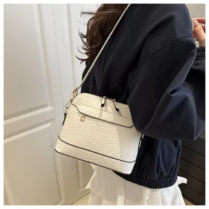Detail of white crocodile pattern shoulder bag with gold zipper on a model