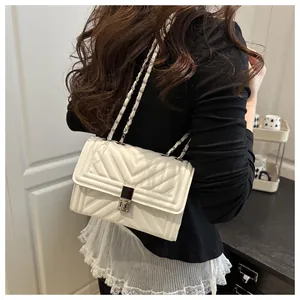 Detail of white quilted handbag featuring silver rotating lock and metal chain strap