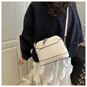 Close-up of white woven leather crossbody bag with black piping and wide shoulder strap