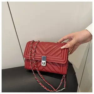 Close-up of red quilted PU leather handbag with silver metallic turn-lock and chain strap