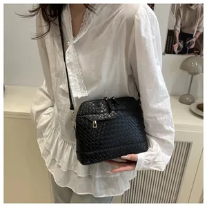 Detail of black woven texture crossbody bag with gold metal zipper on a model