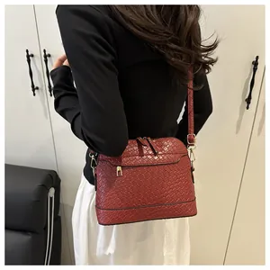 Detail of burgundy woven texture on shoulder bag with premium golden metal zippers