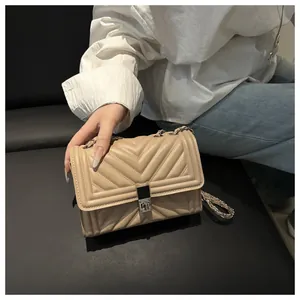 Detail view of beige quilted leather crossbody bag with silver metal buckle and chain