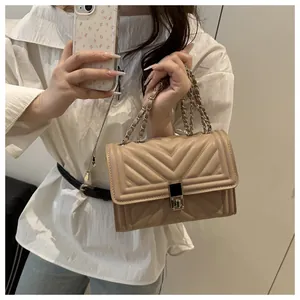Detail of beige quilted chain bag featuring V-shaped stitching and metallic lock closure