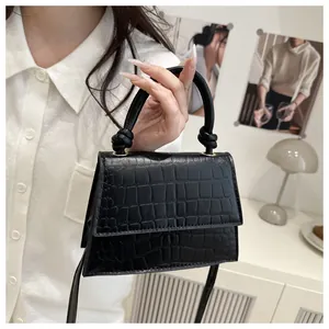 Détail d'un sac à main noir à motif crocodile avec une poignée nouée au design unique
