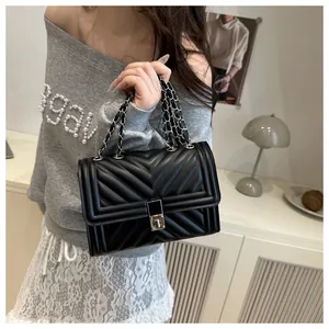 Detail of black quilted leather crossbody bag with silver chain strap and metallic lock