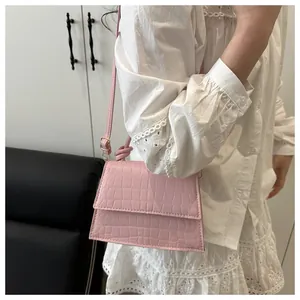 Mannequin portant un sac à main carré rose à motif crocodile avec bandoulière