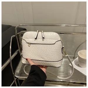 Detailed view of white crocodile pattern cross-body bag with golden hardware and zipper