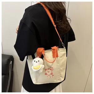 Détail du sac en toile avec bandoulières orange, imprimé ours et breloque peluche