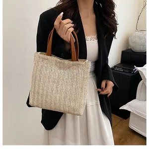 Detail of woven straw tote bag with brown handles and natural textured pattern