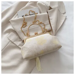 Dettaglio del ricamo floreale beige, manico in metallo e nappa sulla borsa vintage