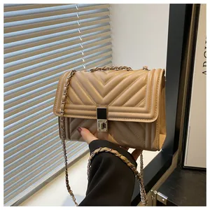 Detailed close-up of the beige V-quilted texture and metal twist lock on the chain bag
