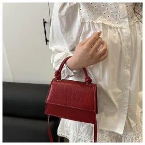 Détail du sac à main rouge à motif crocodile avec poignée nouée et rabat élégant