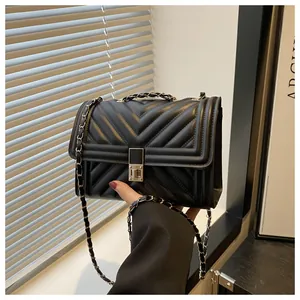 Detail of black quilted leather shoulder bag featuring gold metal buckle and chain strap