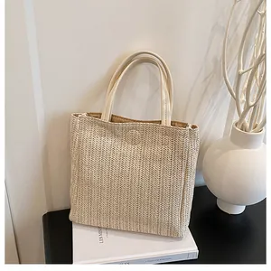Detail of minimalist straw tote bag with cream leather handles and herringbone weave texture