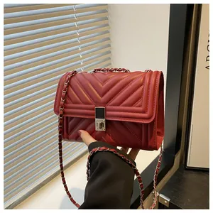 Detail of red quilted leather handbag showing metallic chain strap and V-pattern stitching