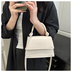 Détail d'un petit sac carré blanc cassé embossé crocodile avec poignée nouée élégante